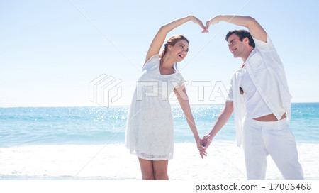 Happy couple forming heart shape with their hands 17006468
