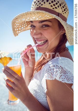 Smiling brunette wearing straw hat and drinking a cocktail 17006786