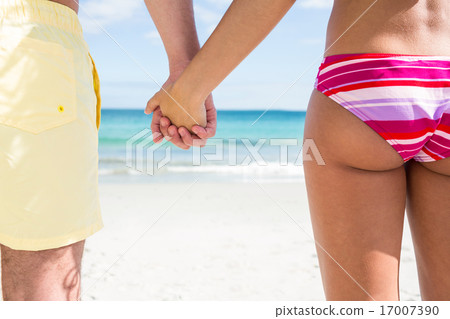 Happy couple holding hands and looking at the sea Happy couple holding hands and looking at the sea 17007390