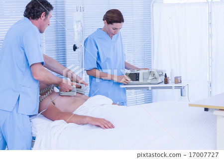 Medical team resuscitating a man with a defibrillator 17007727