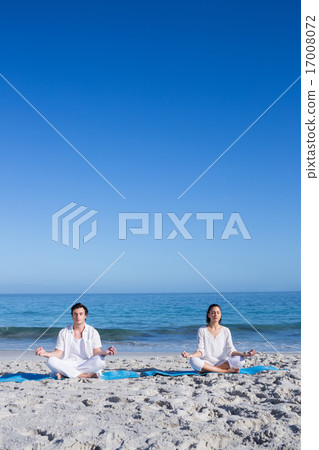 Happy couple doing yoga beside the water 17008072