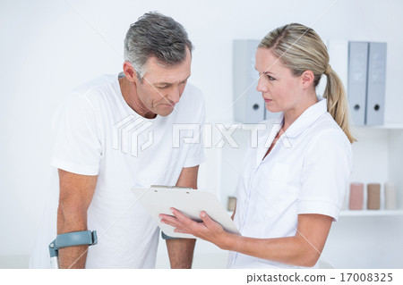 Doctor showing clipboard to her patient with crutch Doctor showing clipboard to her patient with crutch 17008325