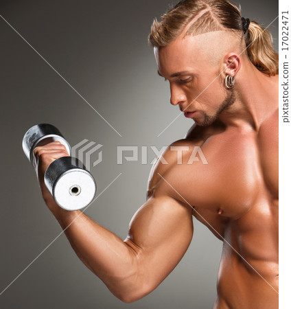 Closeup of a handsome power athletic man bodybuilder doing exercises with dumbbell  17022471