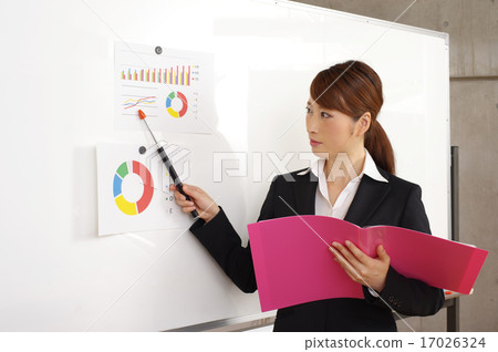 A woman oblique eye line board that points to the white board and gives an explanation of the presentation 17026324
