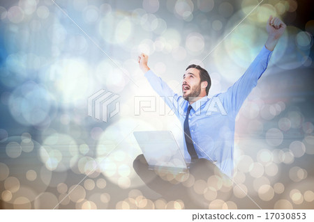 Composite image of excited cheering businessman sitting using hi 17030853