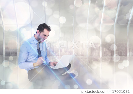 Composite image of cheering businessman sitting using his laptop 17031081