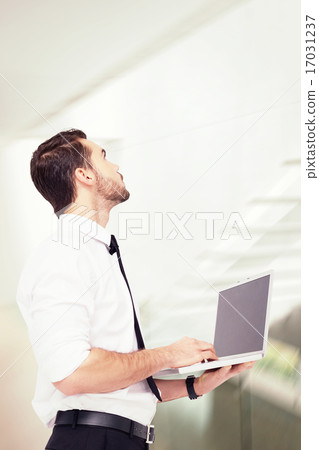 Composite image of sophisticated businessman standing using a la 17031237