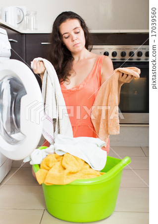Woman tired and washing clothes in machine Woman tired and washing clothes in machine 17039560