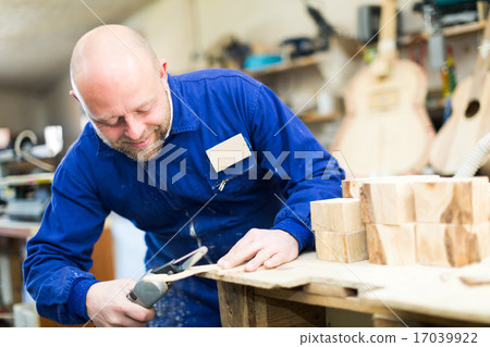 craftsman working with unfinished guitar 17039922
