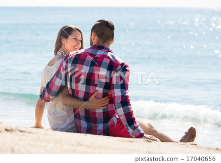 Loving couple sitting on beach sand 17040656