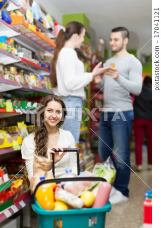 customers standing near shelves with canned goods at shop customers standing near shelves with canned goods at shop 17041121