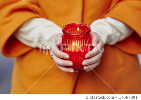 Woman holding burning candle in her hands Woman holding burning candle in her hands 17067091