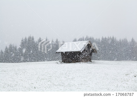 heavy snowstorm over old wooden hut 17068787