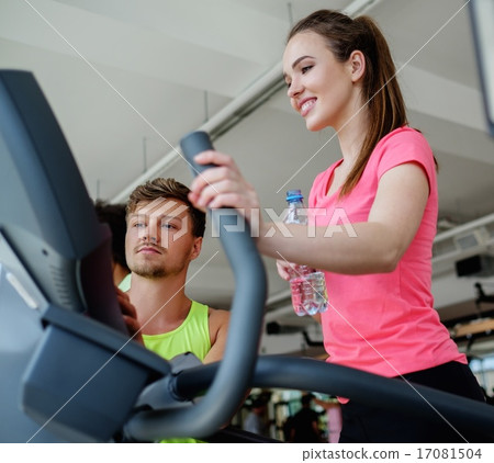 Trainer explaining how to use elliptical training machine 17081504