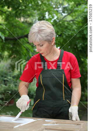 Female worker restoring old wooden door Female worker restoring old wooden door 17085259