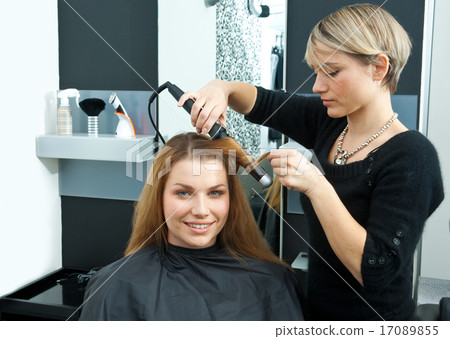 hair stylist curling woman hair in salon hair stylist curling woman hair in salon 17089855