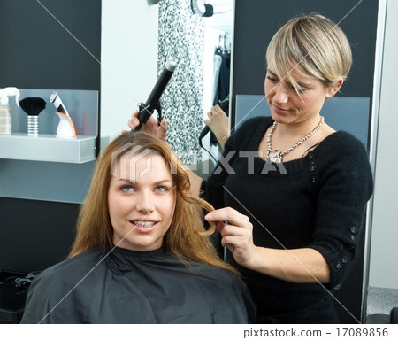 hair stylist curling woman hair in salon hair stylist curling woman hair in salon 17089856