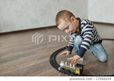 little boy builds toy railroad 17098244