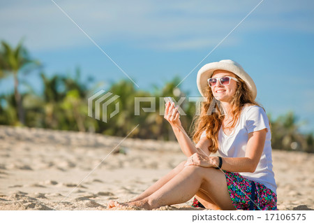 Beautiful young woman on the beach at sunny day with mobile phone Beautiful young woman on the beach at sunny day with mobile phone 17106575