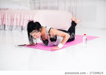 Fit sporty woman in headphones doing push ups home training listening music at smartphone concept Fit sporty woman in headphones doing push ups home training listening music at smartphone concept 17109625