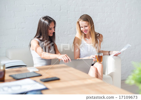 Two business woman friendly discussion during break in office using notebook and drinking coffee. Two business woman friendly discussion during break in office using notebook and drinking coffee. 17109673