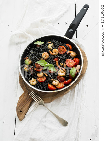 Black pasta spaghetti with shrimps, basil, pesto sauce and slow-roasted cherry-tomatoes in cooking 17110052