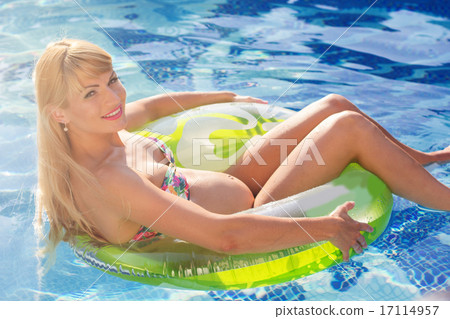 Pregnant woman is swimming with rubber ring in pool Pregnant woman is swimming with rubber ring in pool 17114957