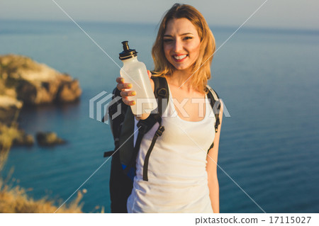 Smiling backpacker girl is holding bottle with water Smiling backpacker girl is holding bottle with water 17115027