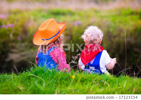 Little boy and girl dressed up as cowboy and cowgirl playing wit Little boy and girl dressed up as cowboy and cowgirl playing wit 17123154