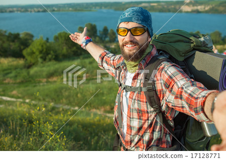 Young caucasian man with backpack standing on the top of hill 17128771