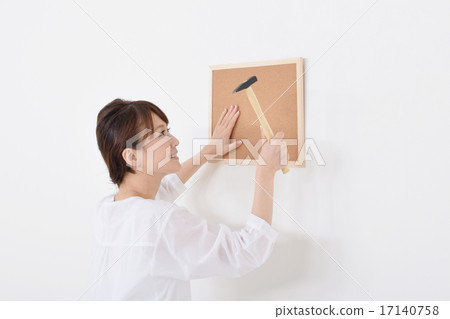 A woman installing a corkboard A woman installing a corkboard 17140758