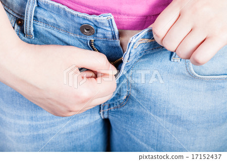 female hand fastens jeans zipper 17152437