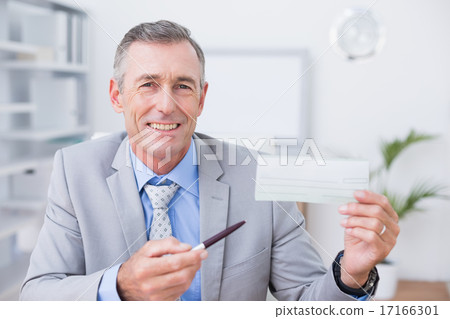 Smiling businessman holding cheque 17166301