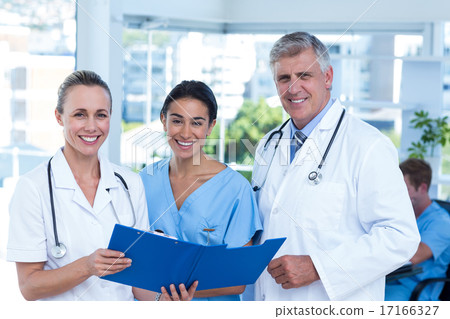 Team of doctors working on their files and smiling at camera Team of doctors working on their files and smiling at camera 17166327