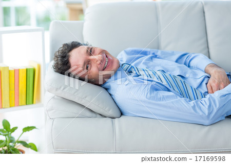 Businessman smiling at camera lying on couch 17169598