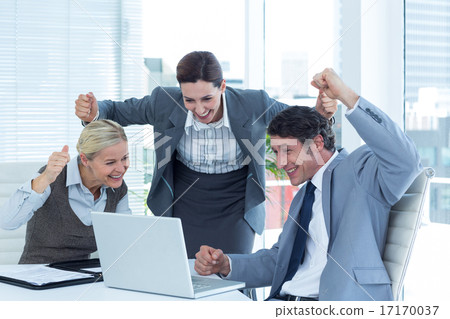 Business people cheering in front of laptop at office 17170037