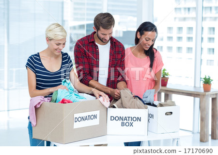 Smiling young friends volunteers separating clothes 17170690