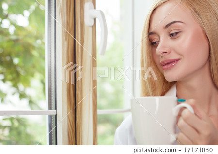 Beautiful young woman is resting on windowsill 17171030