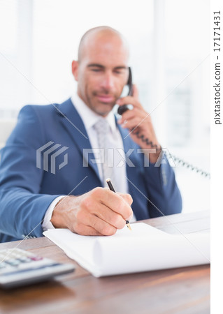 Businessman on the phone and writing notes Businessman on the phone and writing notes 17171431