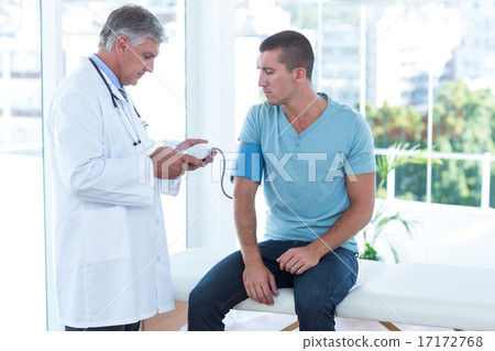 Stock Photo: Doctor examining his patients blood pressure