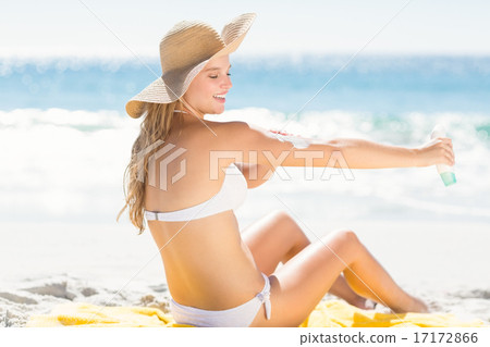 Pretty blonde woman spreading sun tan lotion on her arms 17172866