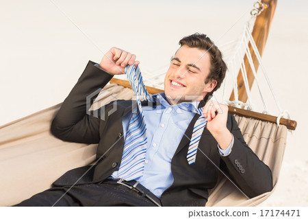 Businessman removing his tie on the hammock Businessman removing his tie on the hammock 17174471