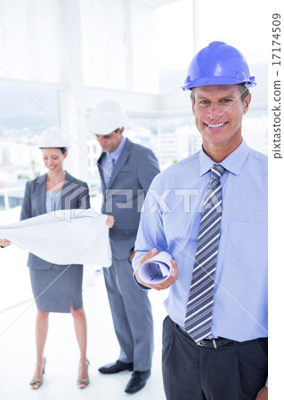 Businessmen and a woman with hard hats and holding blueprint Businessmen and a woman with hard hats and holding blueprint 17174509