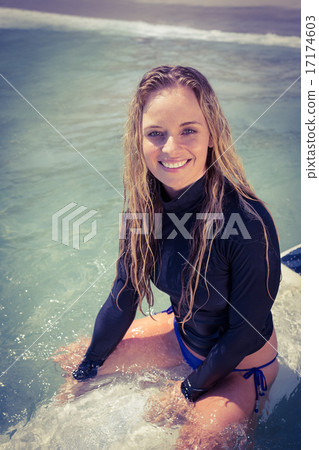 Woman on a surfboard smiling at camera 17174603