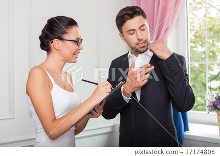 Pretty young tailor is serving her customer 17174808