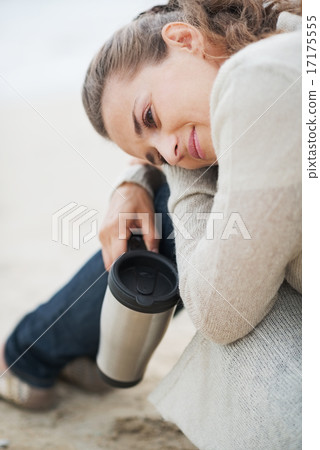 Young woman in sweater sitting with cup of hot beverage and rela Young woman in sweater sitting with cup of hot beverage and rela 17175555