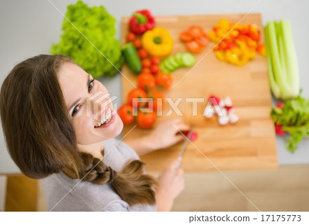 Happy young housewife cutting fresh vegetables 17175773