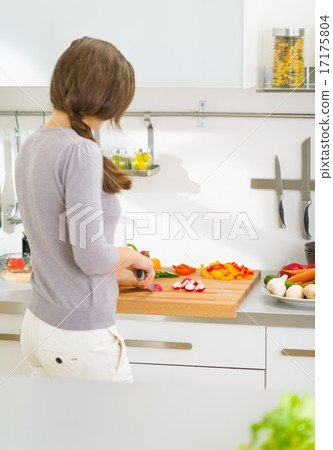 Woman cutting fresh vegetables in modern kitchen . rear view Woman cutting fresh vegetables in modern kitchen . rear view 17175804