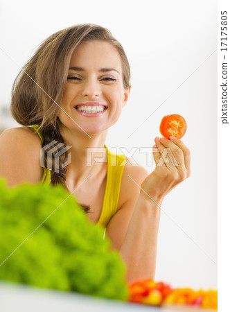 Portrait of happy young woman with tomato in kitchen Portrait of happy young woman with tomato in kitchen 17175805