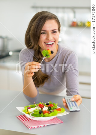 Young woman eating greek salad and watching tv 17175840